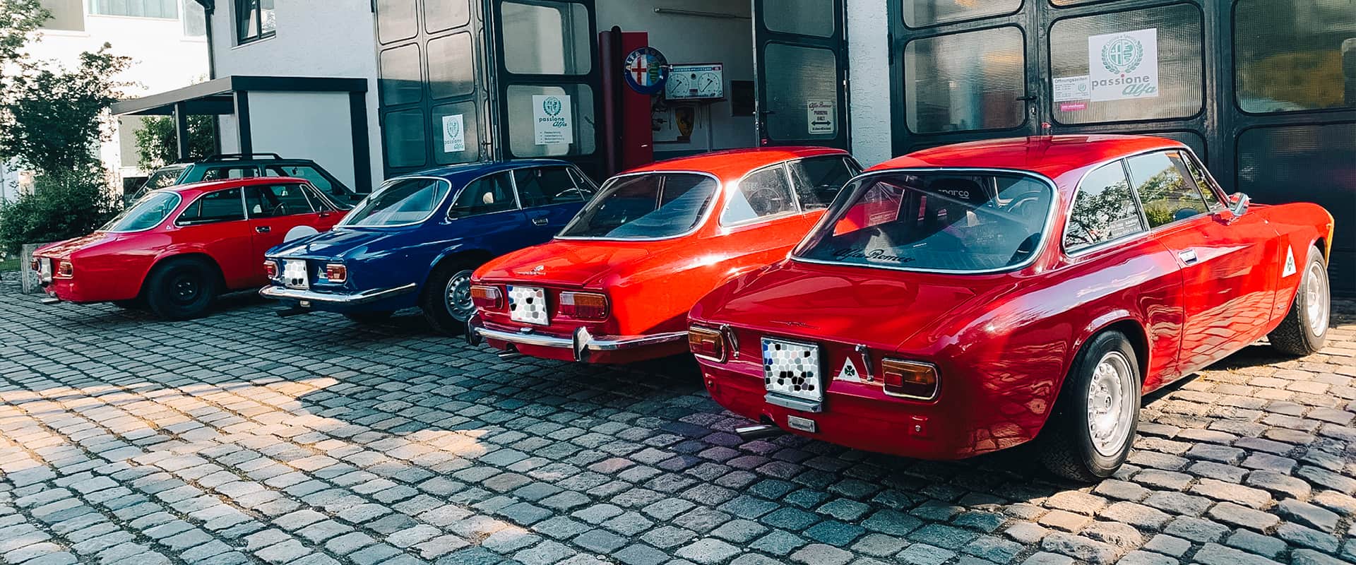 Eine Reihe an Alfa Romeo Bertone vor der Werkstatt Passione Alfa in Oberhaching bei München